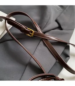 Detail of adjustable brown leather shoulder strap with polished golden metal buckle