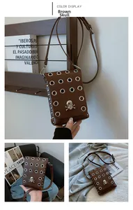 Detail of brown leather crossbody bag with silver skull ornament and metal eyelets