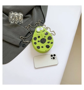 Detailed scale view of a mini green ladybug crossbody bag with silver chain strap