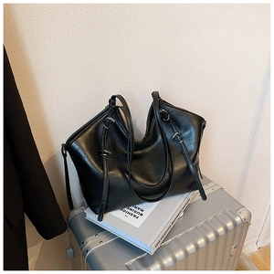 Detailed view of the glossy black leather tote bag with adjustable strap and metal buckle