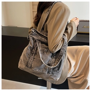 Detail of vintage washed grey denim tote bag with metal buckle pocket and shoulder strap