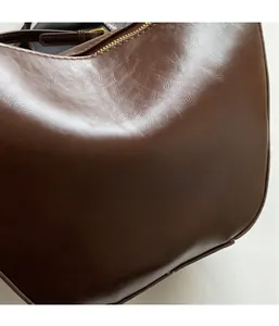 Close-up of vintage dark brown leather grain texture and golden zipper detail on bucket bag