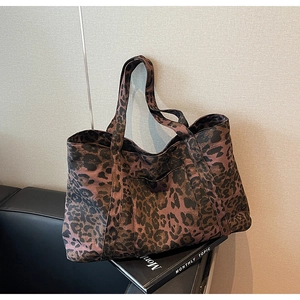 Macro shot of large leopard print tote bag placed on a leather sofa with textured finish