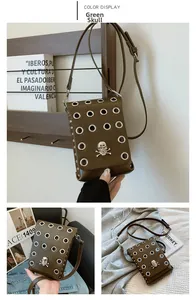 Detail of green crossbody bag featuring silver metal eyelets and skull badge ornament