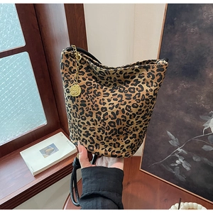 Detail of leopard print tote bag with golden camellia charm and black leather trim