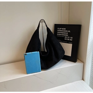 Detailed view of oversized black suede hobo bag with wide strap on marble display