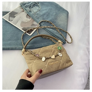 Detail of khaki quilted suede handbag with gold hardware and heart charms