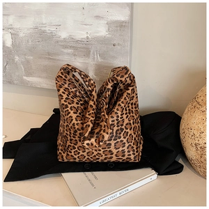 Detailed view of leopard print tote bag placed on a black suit with artistic decor