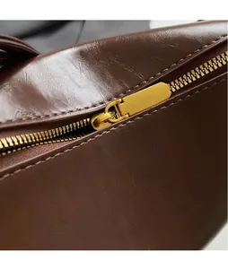 Macro detail of the dark brown leather bag showing a smooth surface and golden metal zipper