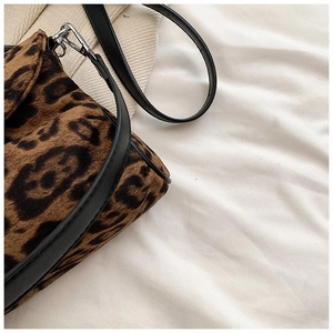 Detailed close-up of the leopard print suede fabric and silver metal hook on the bag