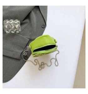 Detail of a bright green circular mini bag with litchi grain texture and metal ball chain