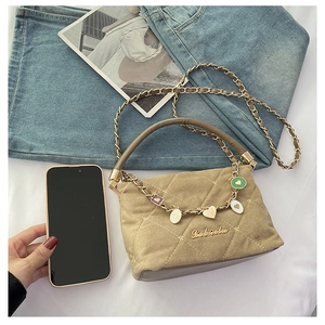 Quilted beige mini handbag with gold chain, heart charm, and phone for size reference