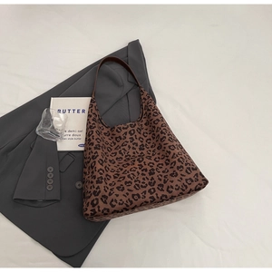 Détail du sac hobo léopard posé sur un blazer gris dans une mise en scène élégante
