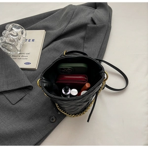 Detailed interior of black quilted bucket bag showing phone, wallet, and lipstick items