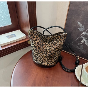 Detail of leopard print bucket bag with knotted straps and gold chain accessory