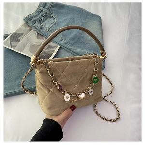 Close-up of quilted light brown handbag with metal chain and colorful babe charms