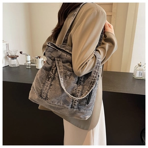 Detail view of washed denim tote bag with metal zipper and practical side pocket design