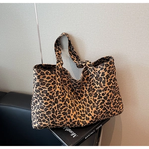 Detail showing the thick leopard print canvas texture and wide shoulder strap of tote bag