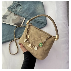 Detail of beige quilted handbag with hard handle and heart-shaped metal charms