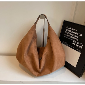 Macro detail of brown suede tote bag featuring a minimalist texture and smooth zipper closure