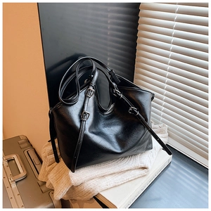 Detail of black tote bag showing fine lychee grain leather texture and adjustable strap buckle