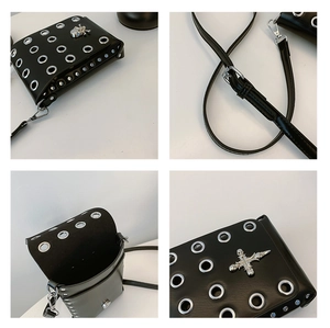 Detail view of black punk crossbody bag with skull cross charm and silver metal eyelets