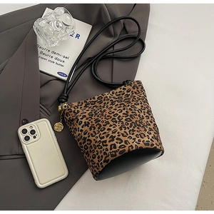 Flat lay of leopard print bucket bag with gold rose charm and black leather base