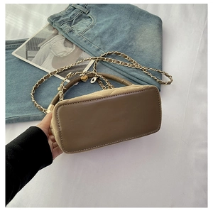 Close-up of brown textured crossbody bag with quilted base and heart-shaped metal charms