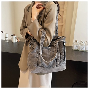 Detailed side view of washed gray denim tote bag with functional pockets and long strap