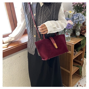Close-up of wine red suede bucket bag featuring a sleek gold rectangular metal clasp