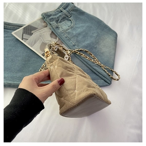 Detail of light brown quilted handbag with gold handle and metal chain strap