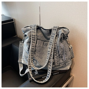 Detail shot of washed blue denim tote bag texture with metal snap button and pocket