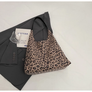 Détail du sac cabas hobo avec imprimé léopard vintage et bandoulière en cuir noir sur costume