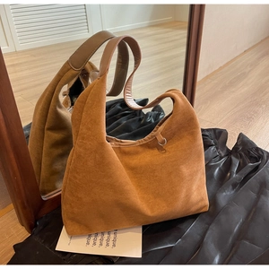 Détail macro d'un sac hobo en daim caramel avec bandoulière large et boucle en métal