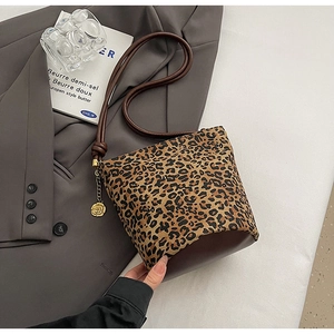 Detailed view of leopard print tote bag featuring a golden rose charm and leather base