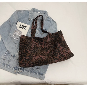 Flat lay view of a large leopard print canvas tote bag styled with denim and books