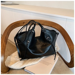 Close-up of black leather tote bag with silver adjustable buckles on wooden chair