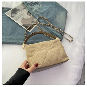 Detail of khaki quilted small square bag with brown leather handle and gold hardware chain