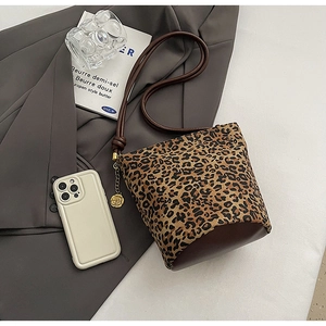 Flat lay of leopard print tote bag with brown faux leather base and gold flower charm
