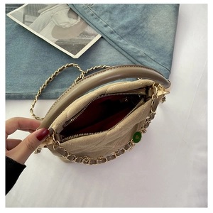 Detail view of beige quilted handbag showing red interior lining and gold chain strap