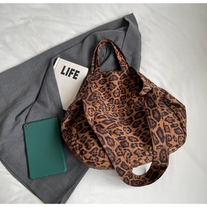 Close-up of leopard print tote bag on a white surface with professional workspace props