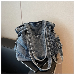 Detail of blue washed denim tote bag with adjustable strap and metal hardware