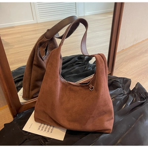 Détail du sac bandoulière en daim marron doux montrant la texture mate et la sangle