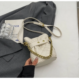 Detailed view of white quilted bucket bag featuring golden chain handle and drawstring