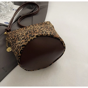 Detail of leopard print fabric tote bag with brown leather bottom and gold flower charm