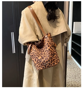Detail of leopard print bucket bag featuring brown leather straps and gold logo accent