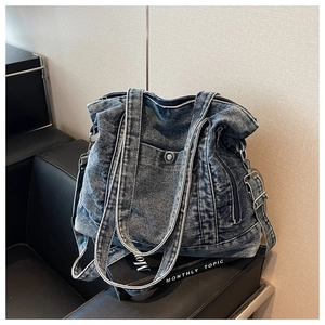Detail view of washed denim tote bag with front snap pocket and side zipper accents