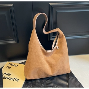 Détail du sac fourre-tout en daim marron avec texture mate et bandoulière sur cuir noir