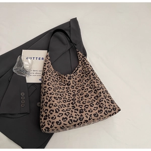 Détail du sac cabas à imprimé léopard avec anses noires sur fond de tissu minimaliste