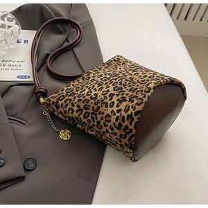 Detail of leopard print tote bag featuring brown leather trim and gold rose charm